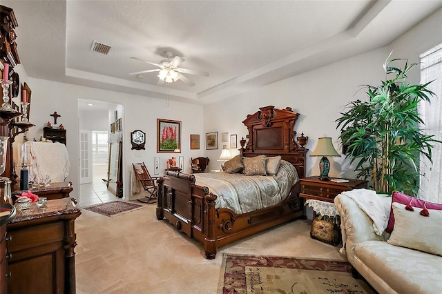 bedroom with light colored carpet, a raised ceiling, visible vents, and multiple windows