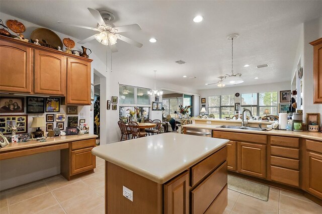 kitchen featuring brown cabinetry, built in study area, a center island, pendant lighting, and a sink