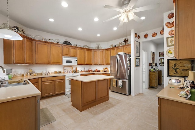 kitchen featuring brown cabinets, light countertops, a kitchen island, a sink, and white appliances