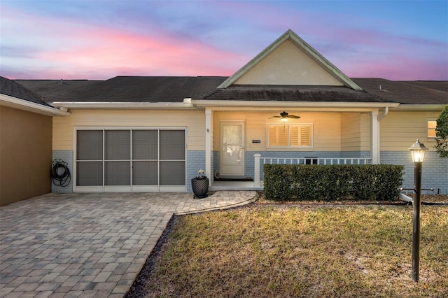 view of front of property with a garage, brick siding, decorative driveway, and a lawn