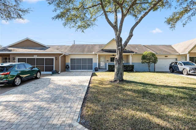 view of front of property featuring brick siding, decorative driveway, an attached garage, and a front yard