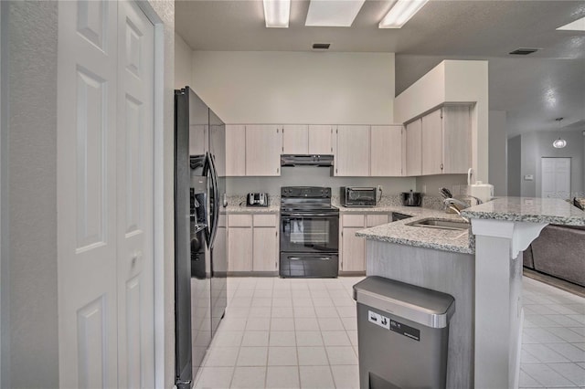 kitchen featuring light tile patterned flooring, a sink, a peninsula, under cabinet range hood, and black appliances