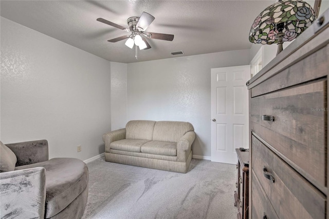 living room featuring a ceiling fan, light colored carpet, visible vents, and baseboards