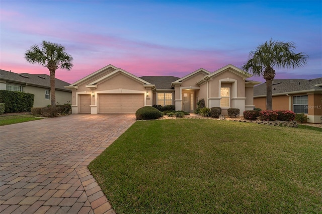 single story home with an attached garage, a yard, decorative driveway, and stucco siding