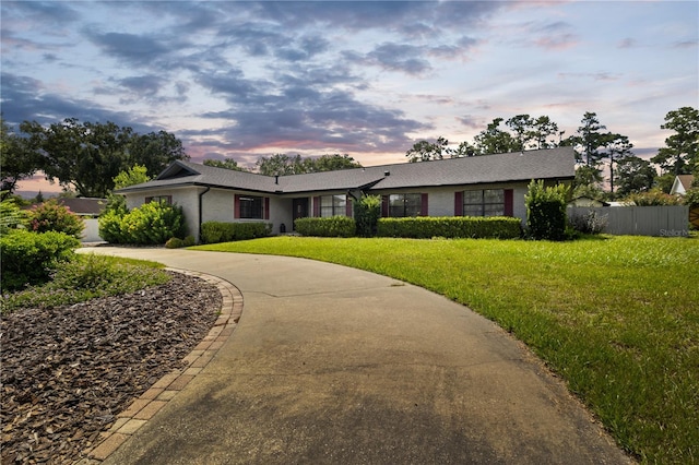 single story home featuring concrete driveway, brick siding, a front yard, and fence