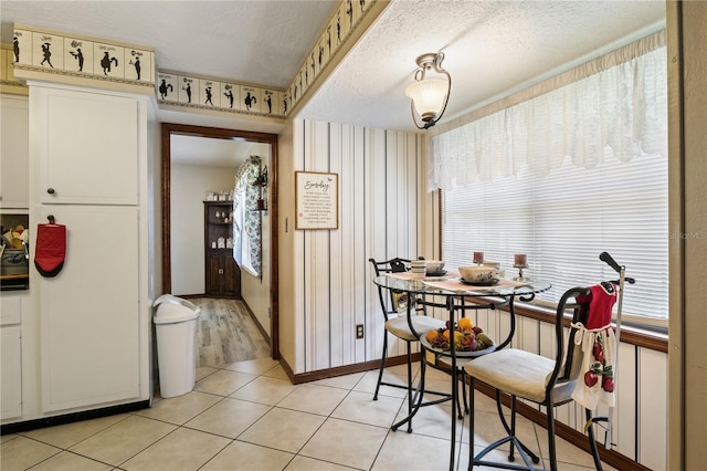 kitchen featuring light tile patterned flooring, a textured ceiling, baseboards, and wallpapered walls