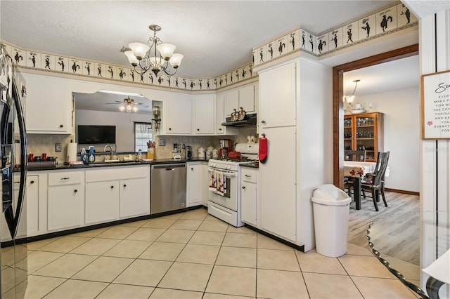 kitchen featuring under cabinet range hood, a sink, white gas range oven, dishwasher, and dark countertops