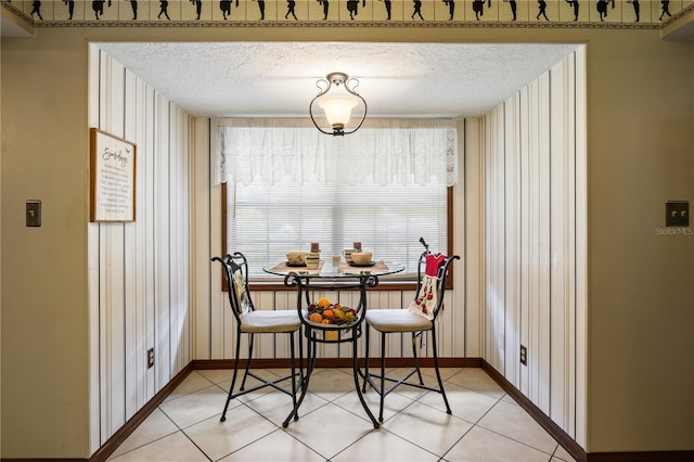 dining space with a textured ceiling, baseboards, and light tile patterned floors