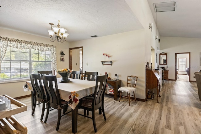 dining space featuring a chandelier, light wood-type flooring, visible vents, and a textured ceiling