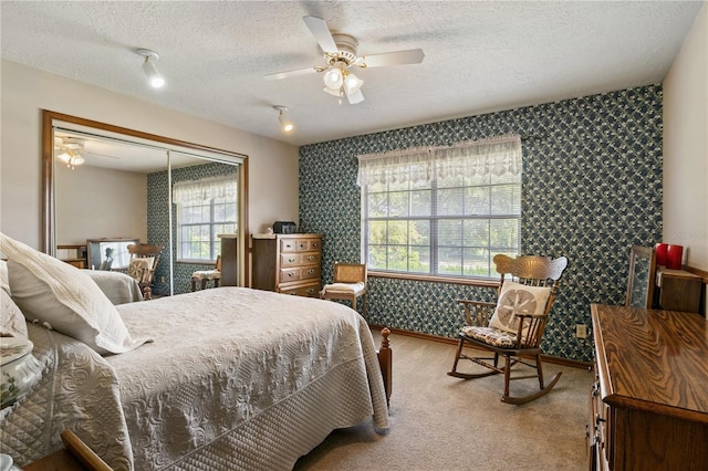 carpeted bedroom featuring ceiling fan, a textured ceiling, baseboards, and wallpapered walls