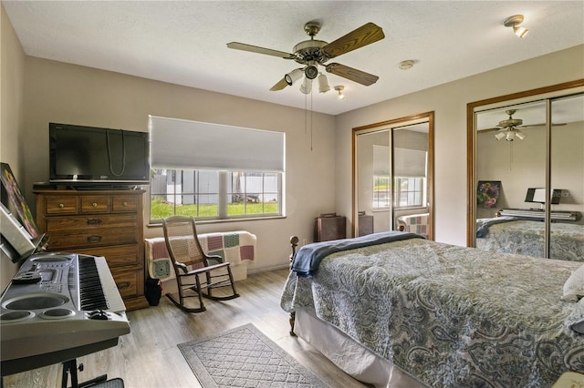 bedroom featuring a ceiling fan, wood finished floors, a textured ceiling, and two closets