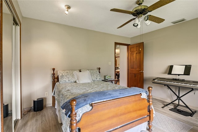 bedroom with ceiling fan, wood finished floors, visible vents, and baseboards