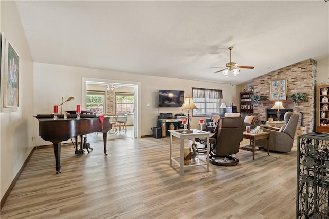 living room featuring lofted ceiling, light wood finished floors, ceiling fan, and a fireplace