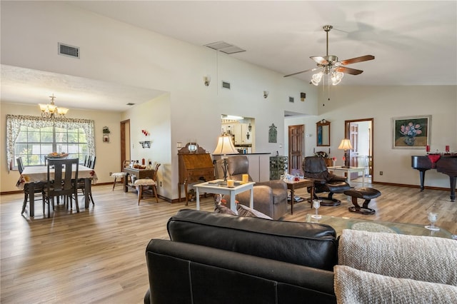 living area with high vaulted ceiling, baseboards, visible vents, and light wood finished floors