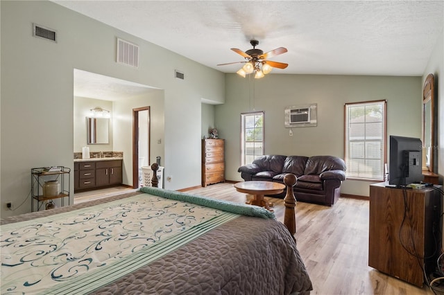 bedroom with lofted ceiling, an AC wall unit, and visible vents