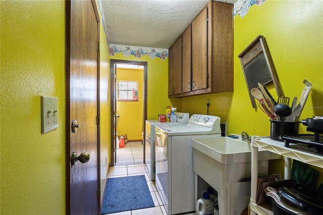 laundry area featuring light tile patterned flooring, cabinet space, a textured ceiling, and separate washer and dryer