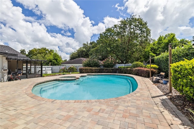 view of pool with a pool with connected hot tub, a patio area, and fence