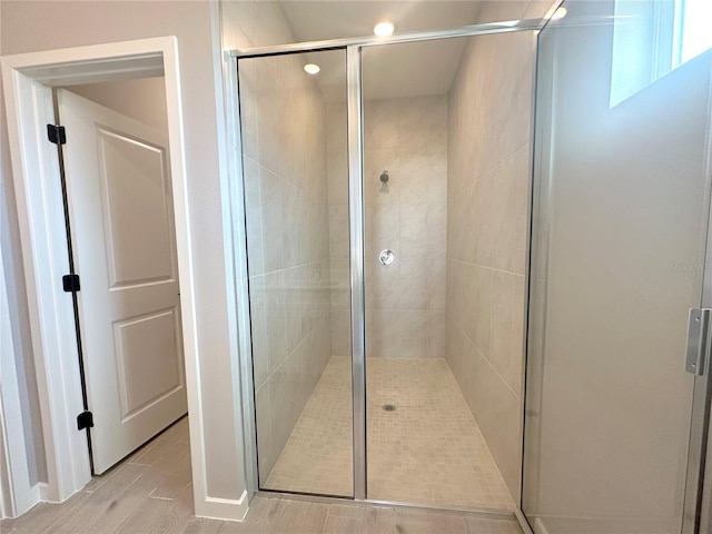 bathroom with hardwood / wood-style floors and a shower with shower door