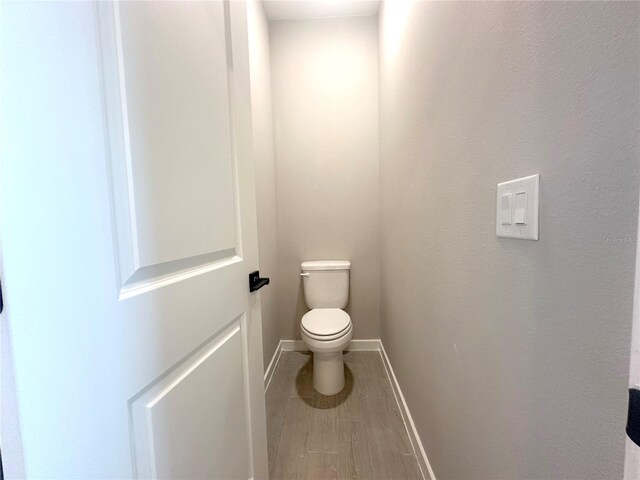 bathroom featuring toilet and wood-type flooring