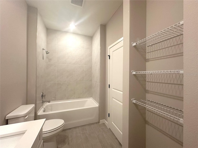 full bathroom featuring toilet, vanity, and tiled shower / bath