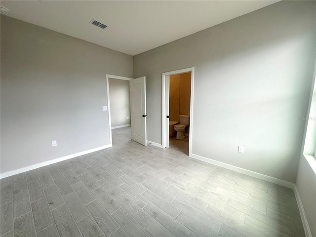 unfurnished bedroom featuring light hardwood / wood-style flooring and connected bathroom