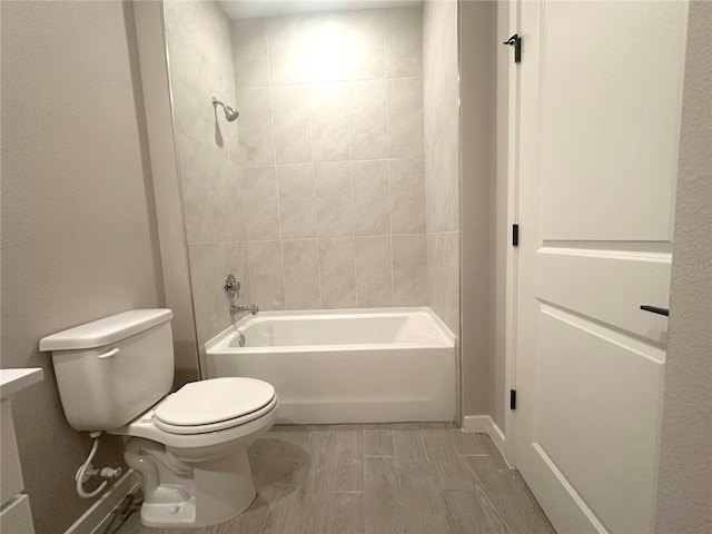 bathroom featuring toilet, hardwood / wood-style floors, and tiled shower / bath combo