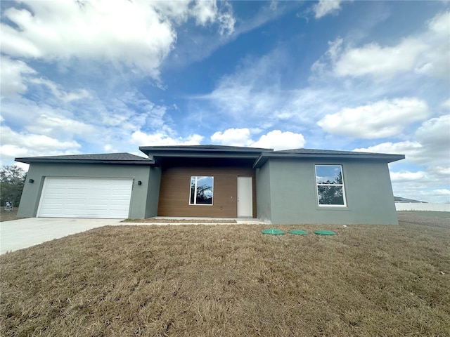 view of front of home with a garage, driveway, a front yard, and stucco siding