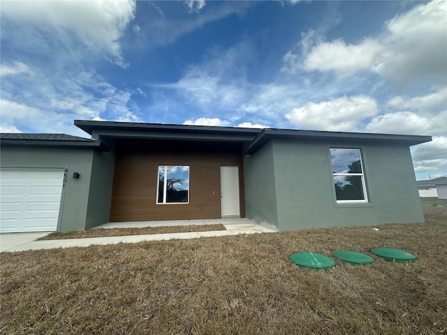 view of front of property featuring a garage, a front lawn, and stucco siding