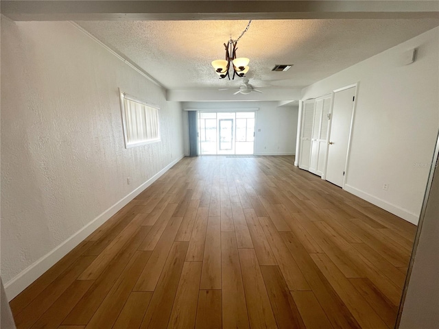 interior space with an inviting chandelier, a textured ceiling, and hardwood / wood-style floors