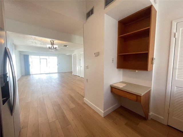 corridor with light hardwood / wood-style floors and a notable chandelier