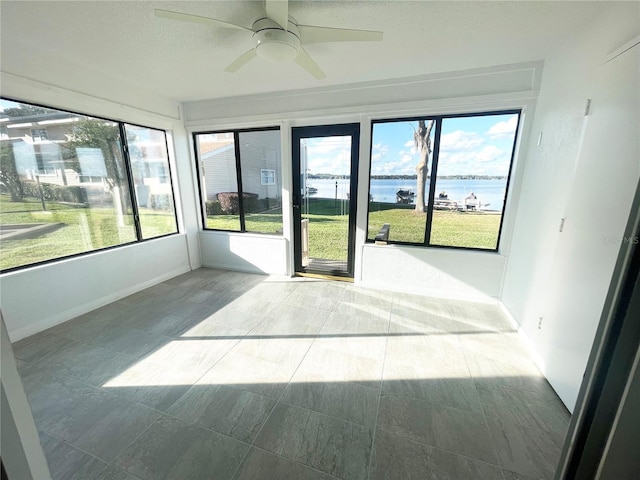 unfurnished sunroom with a water view, ceiling fan, and a healthy amount of sunlight