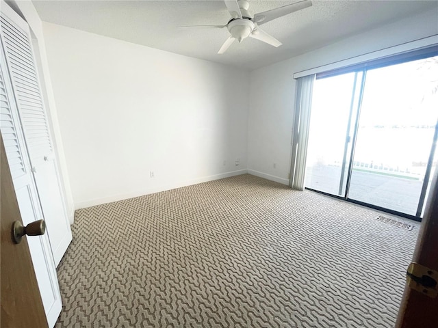 empty room with a textured ceiling, carpet flooring, and ceiling fan