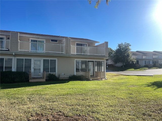 back of house featuring a balcony and a lawn