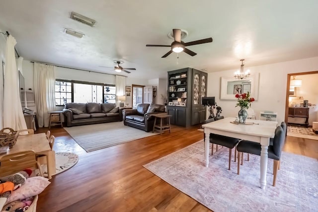 dining space with hardwood / wood-style flooring and ceiling fan with notable chandelier