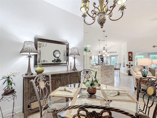 dining room featuring a towering ceiling, an inviting chandelier, and baseboards