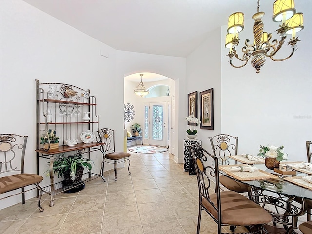 dining room with arched walkways, light tile patterned flooring, a notable chandelier, and baseboards