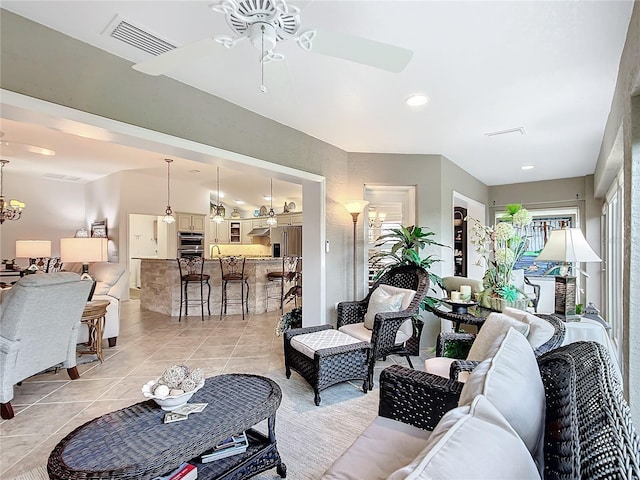 living room with light tile patterned floors, visible vents, and ceiling fan with notable chandelier