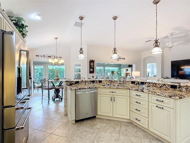 kitchen featuring appliances with stainless steel finishes, stone counters, cream cabinetry, and pendant lighting