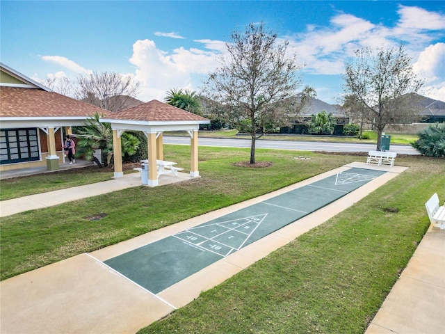 view of community with shuffleboard and a yard