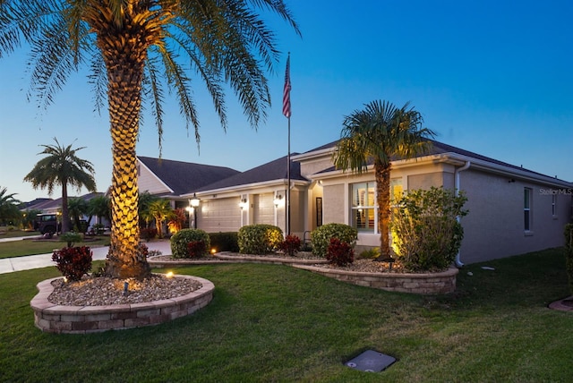 ranch-style home with stucco siding, driveway, a front lawn, and an attached garage