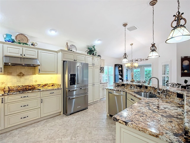 kitchen featuring under cabinet range hood, cream cabinetry, appliances with stainless steel finishes, and a sink