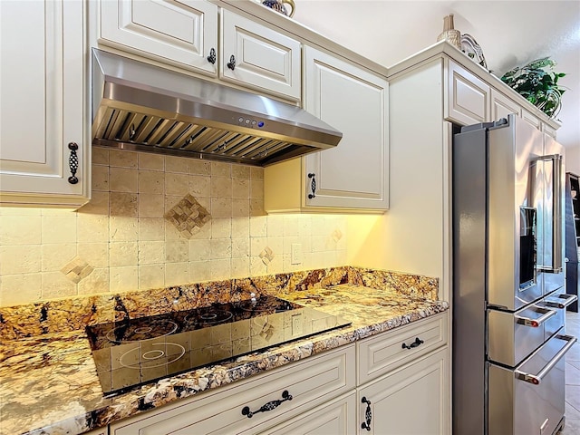 kitchen with stainless steel refrigerator with ice dispenser, under cabinet range hood, backsplash, white cabinets, and black electric cooktop