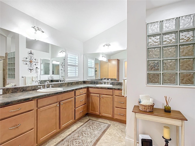 bathroom featuring vaulted ceiling, double vanity, tile patterned floors, and a sink