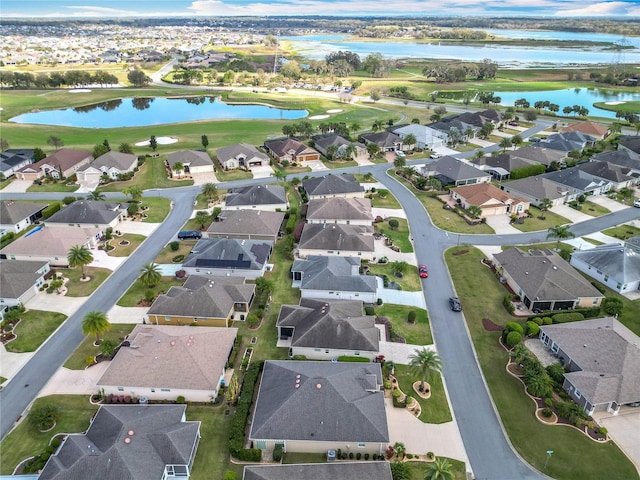 drone / aerial view with a residential view, view of golf course, and a water view