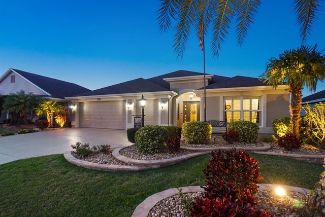 view of front facade featuring concrete driveway, an attached garage, a front lawn, and stucco siding
