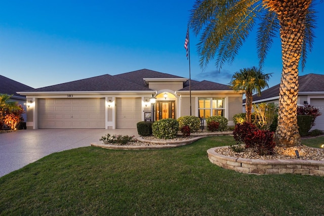view of front facade with a front yard, driveway, a shingled roof, stucco siding, and a garage