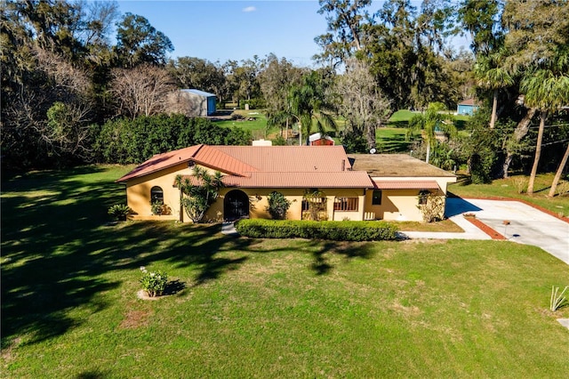 view of front of house with a front yard, concrete driveway, a tile roof, and stucco siding