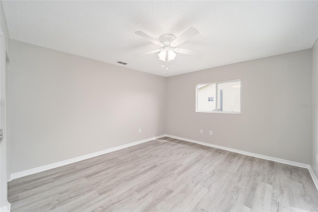 empty room with ceiling fan, light wood finished floors, visible vents, and baseboards