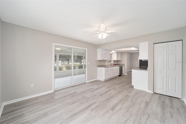 kitchen featuring stainless steel dishwasher, a ceiling fan, white cabinets, light wood-type flooring, and baseboards