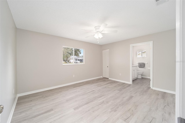 unfurnished bedroom with light wood finished floors, a ceiling fan, connected bathroom, a textured ceiling, and baseboards